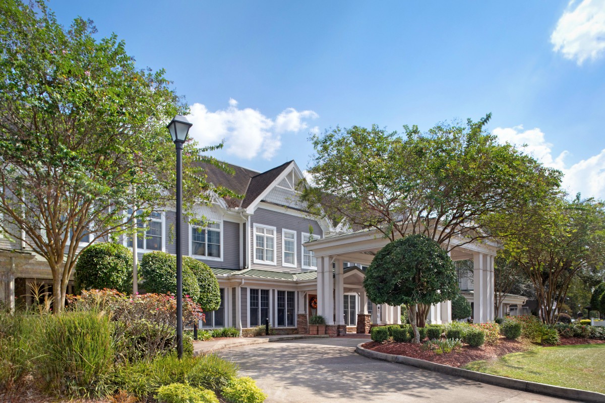 A picturesque residential building surrounded by trees under a clear blue sky.