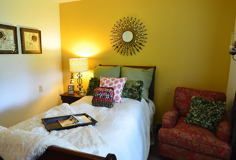 A cozy bedroom with a neatly made bed, decorative pillows, and a warm lamp on the nightstand.