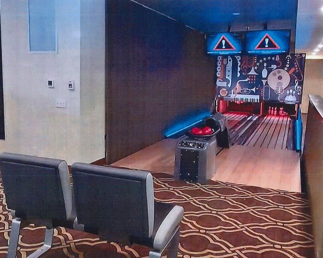 An indoor bowling alley with a seating area and carpeted floor.