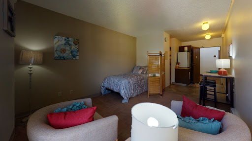 A cozy bedroom featuring a bed, seating area with colorful cushions, and an inviting ambiance.