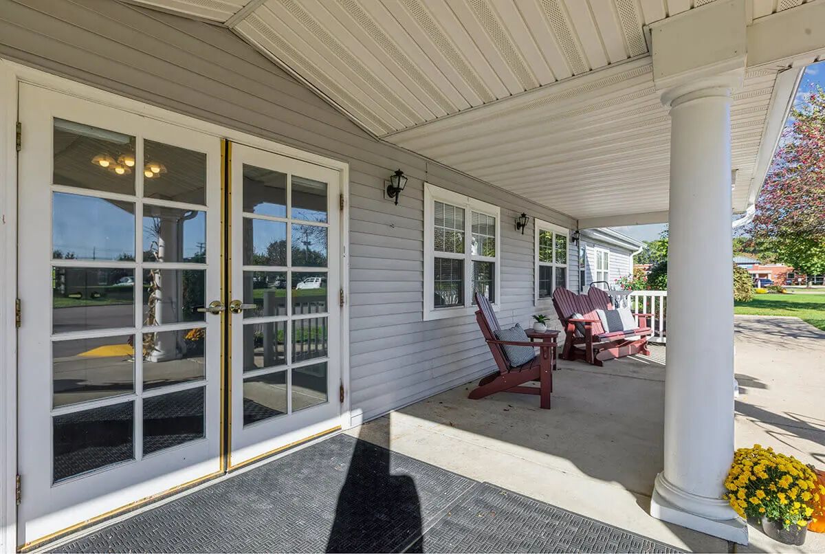 A cozy covered porch with outdoor seating and French doors, providing a relaxing space to enjoy the outdoors.
