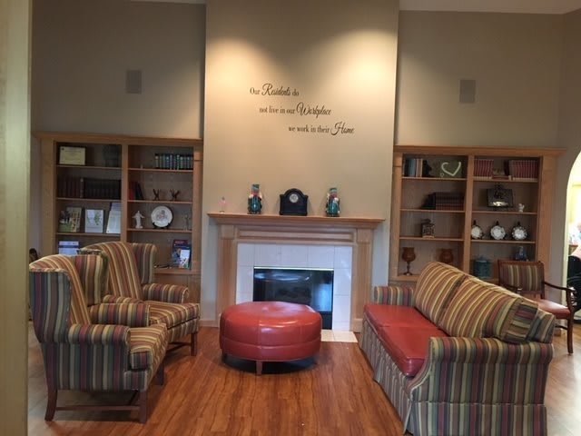 A cozy living room with a fireplace, surrounded by bookshelves and comfortable seating.