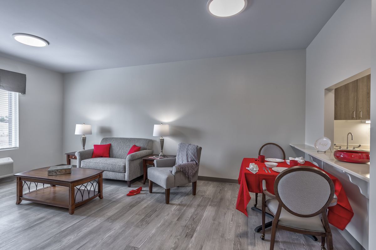 A modern living and dining area featuring a comfortable sofa and chairs, with red accents adding a pop of color.