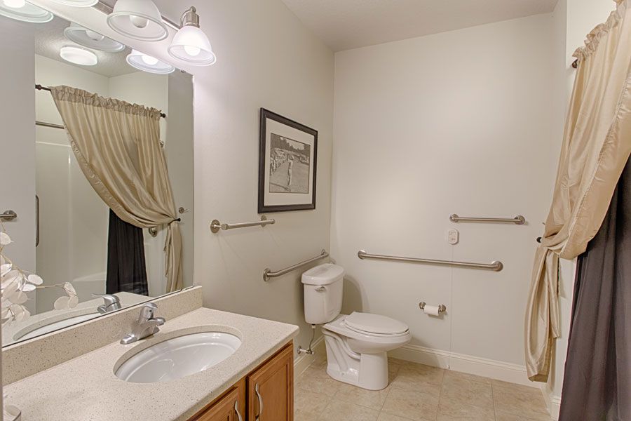 A clean and well-lit bathroom with a sink, toilet, and mirror.