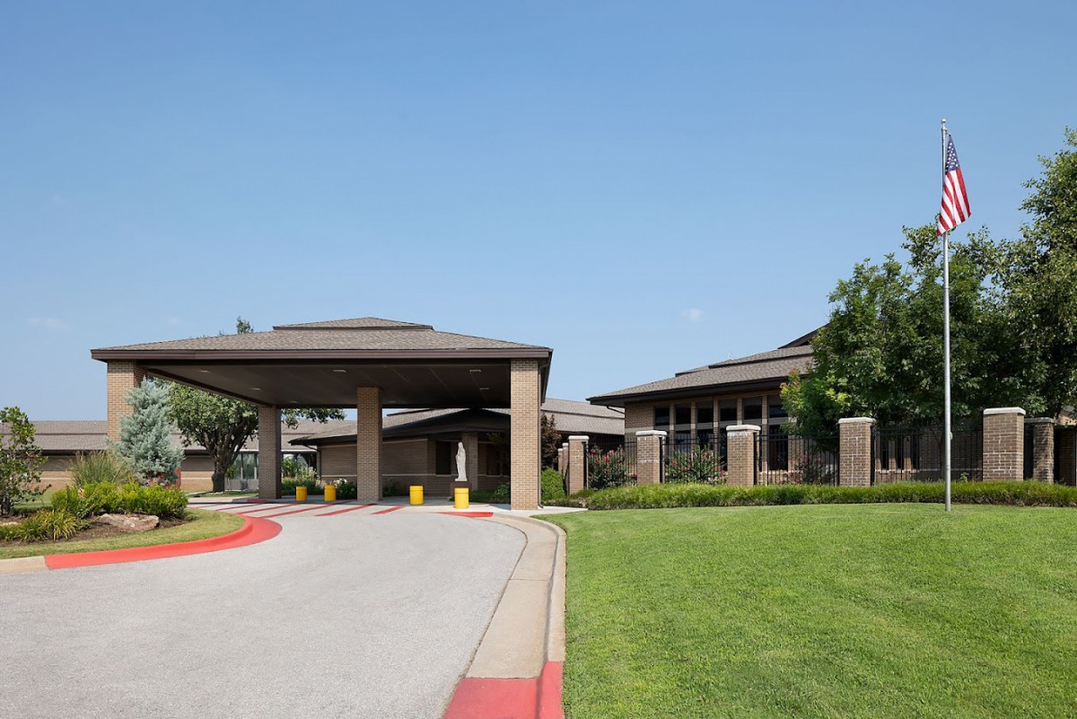 A modern building with a covered entrance and landscaped surroundings.