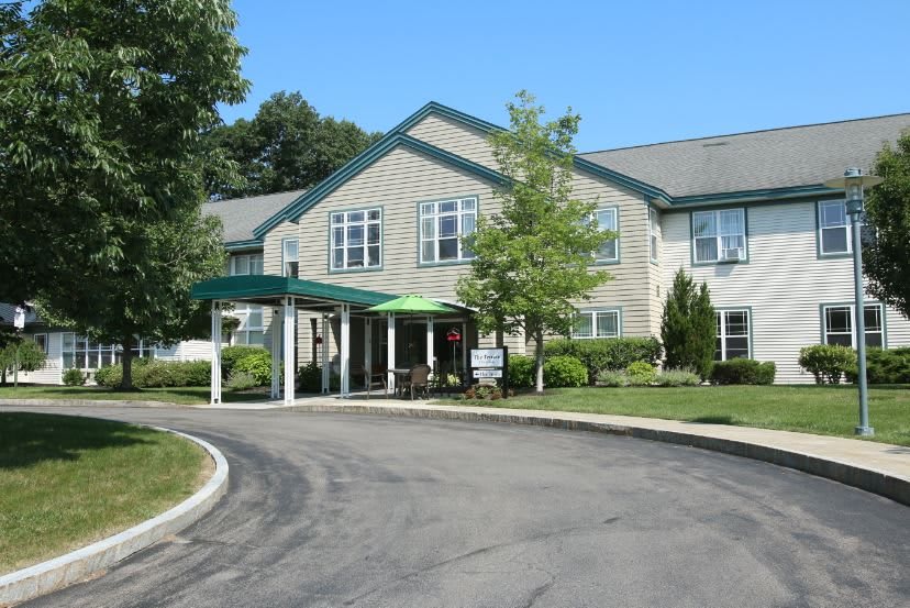 A residential building with a covered entrance, surrounded by trees and landscaping.