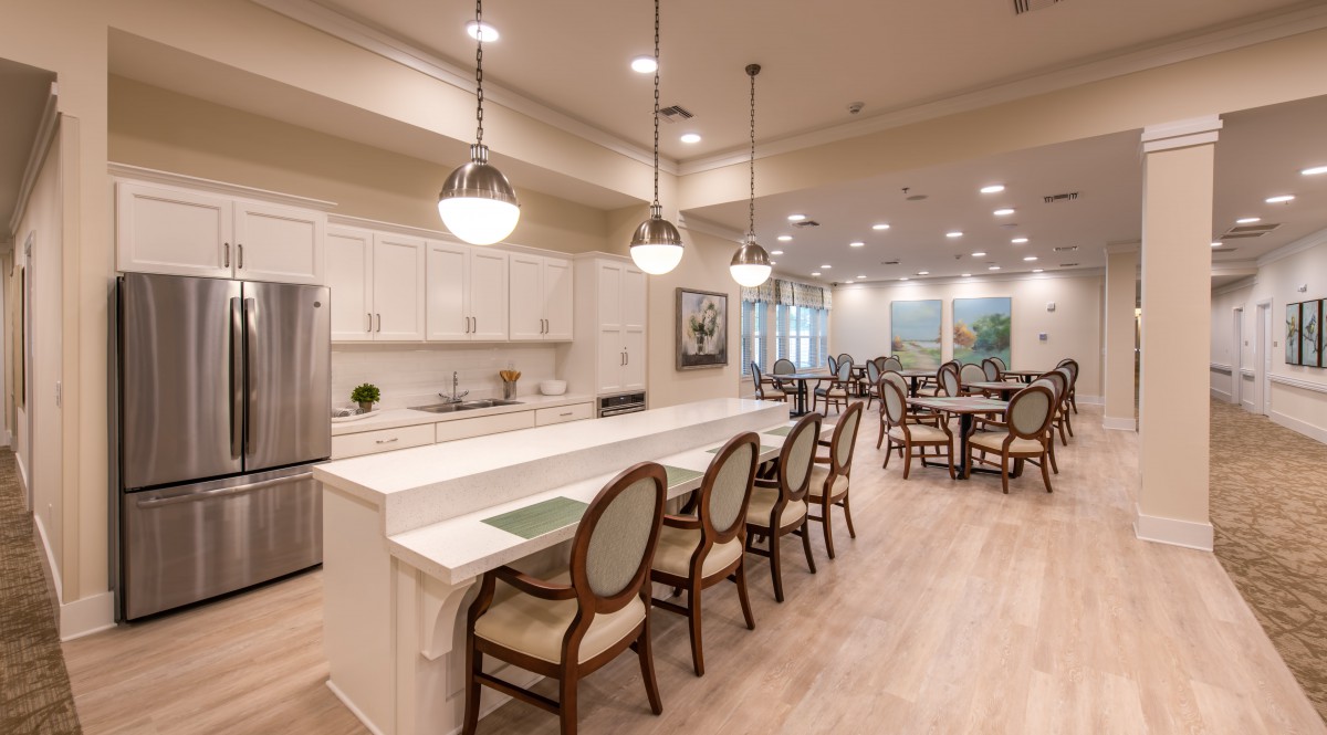 A modern kitchen with an adjacent dining area featuring sleek countertops, elegant chairs, and contemporary lighting.
