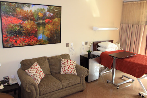 A cozy living space featuring a comfortable sofa, a neatly made bed, and a vibrant painting on the wall.