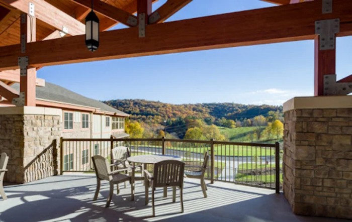 A spacious balcony with outdoor seating overlooks a scenic landscape.