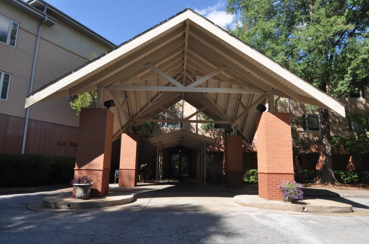 A spacious covered entrance with brick pillars leading into a building.