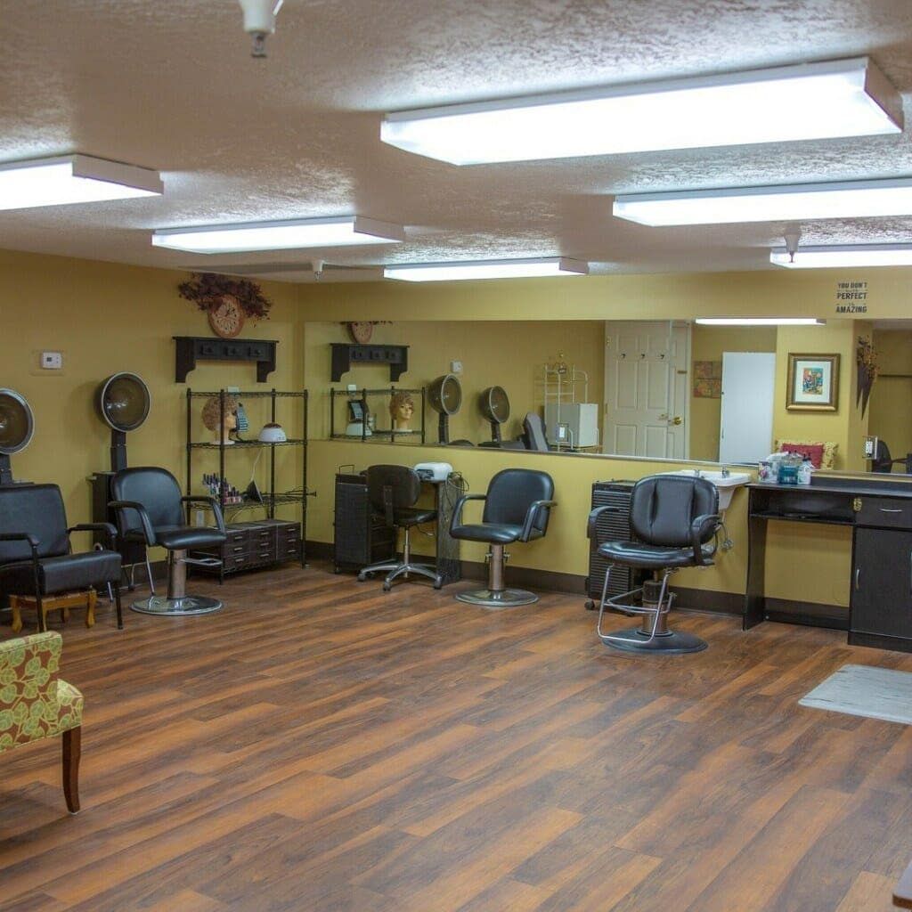 An empty hair salon with multiple styling stations and wooden flooring.