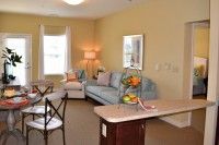 A cozy living room with a sofa, lamp, and a table adorned with fruit.
