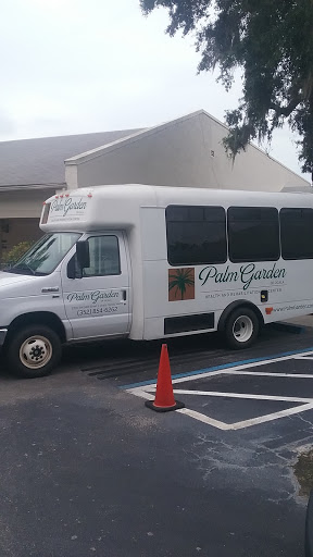 A shuttle bus parked in a lot, advertising Palm Garden.