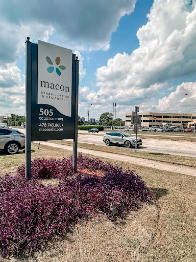 Sign showing the location and name of a business with a landscaped entrance.