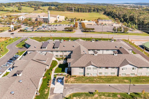 Aerial view of a residential complex surrounded by open fields and a parking area.