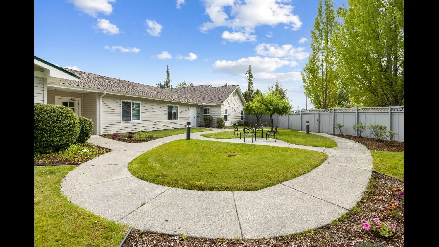A spacious backyard with a well-maintained lawn and winding pathways surrounded by a wooden fence.