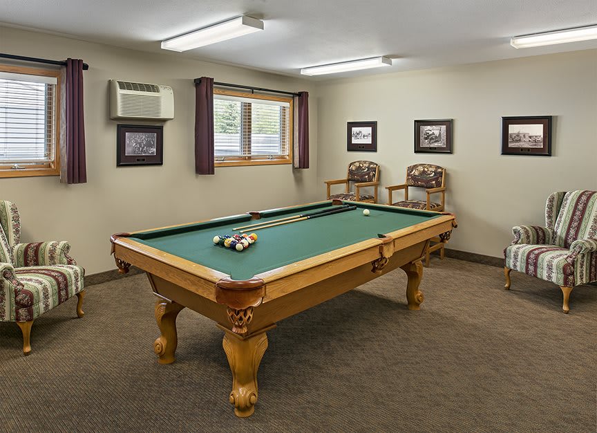 A cozy game room featuring a pool table with vibrant green felt and classic wooden accents.