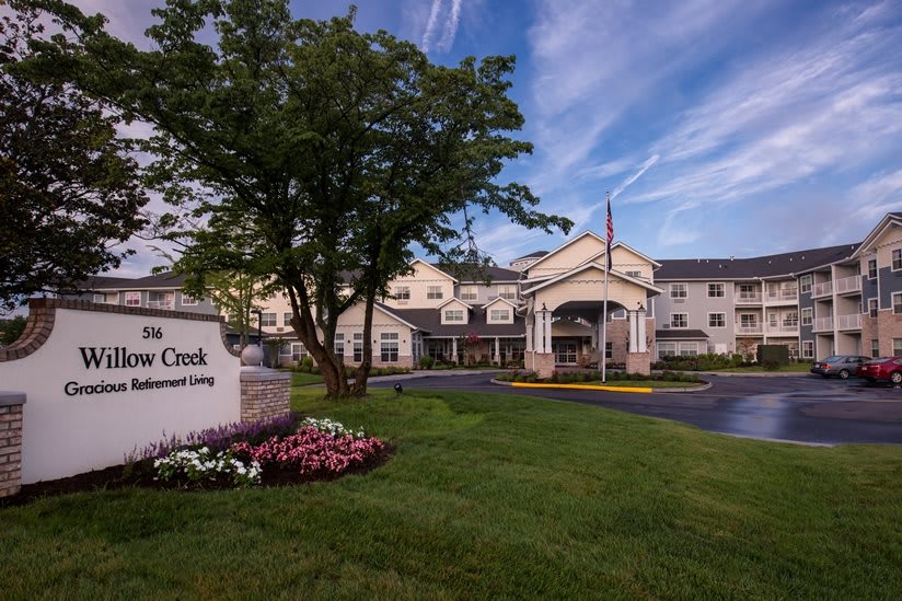 A picturesque view of a residential building with a well-maintained garden and entrance sign against a clear sky.
