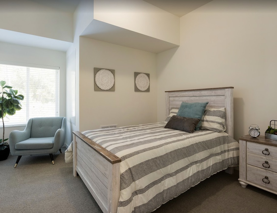 A cozy bedroom with a striped bedding set and neutral decor.