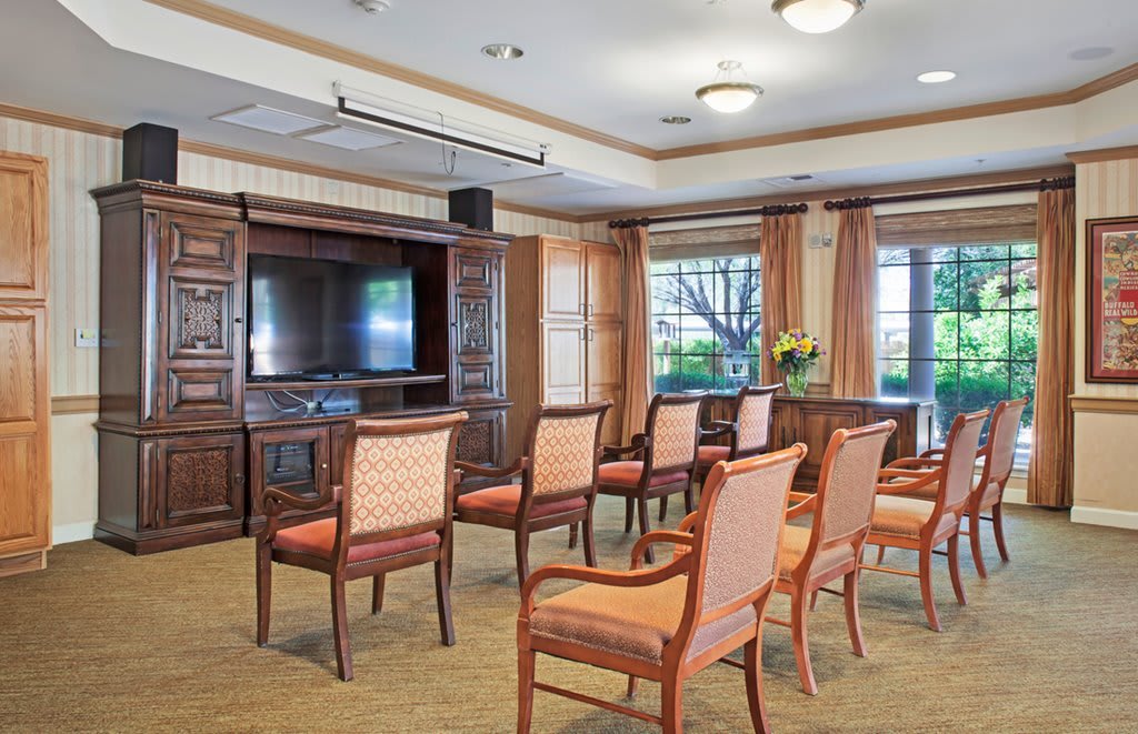 A small conference room with chairs arranged in rows facing a large television.