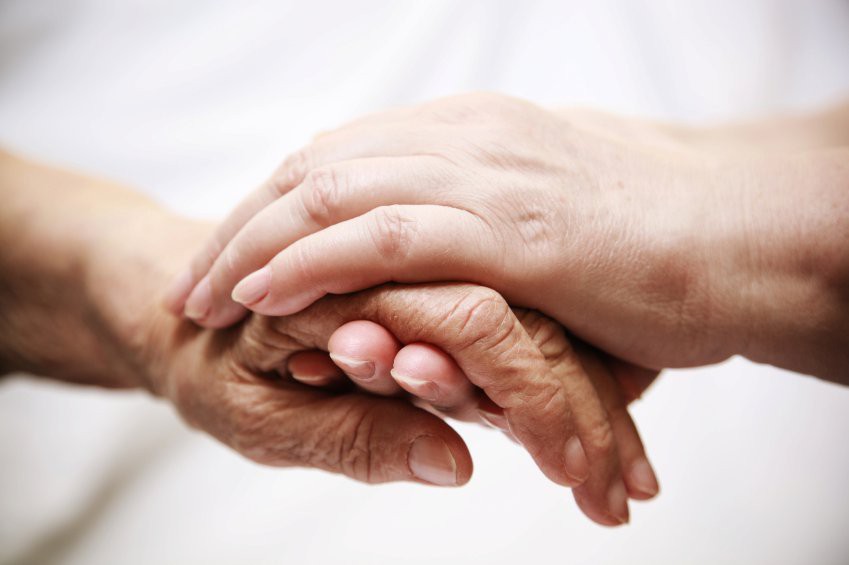 A pair of hands gently holding another in a gesture of support and care.