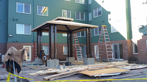 Construction of an outdoor shelter with workers and ladders on site.