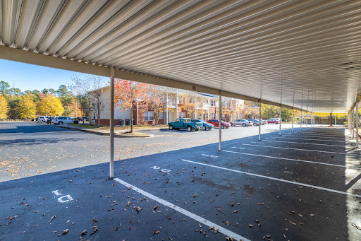 A view of a covered parking area with colorful autumn trees and parked cars.