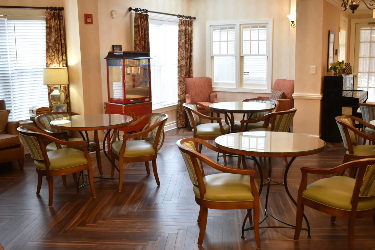 A cozy cafe interior with tables and chairs, featuring a popcorn machine by the window.