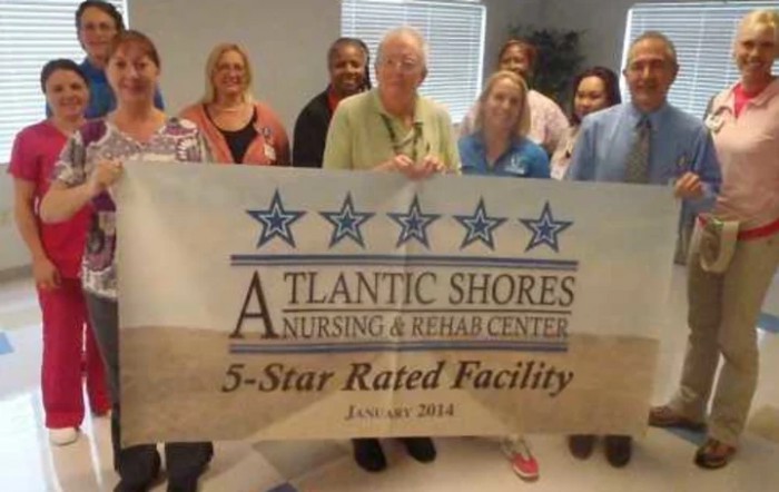 A group of people holding a banner for Atlantic Shores Nursing & Rehab Center, a 5-star rated facility.