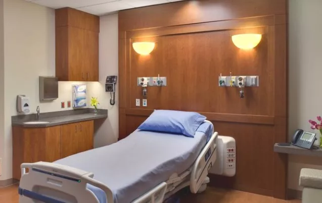 A clean and modern hospital room with a neatly made bed and medical equipment.
