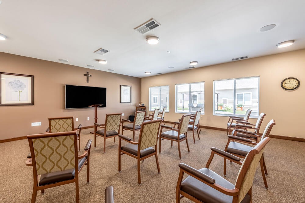 A small chapel with arranged seating and a television on the wall.