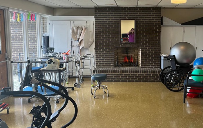 A basement room featuring a brick fireplace, various chairs, and tables.
