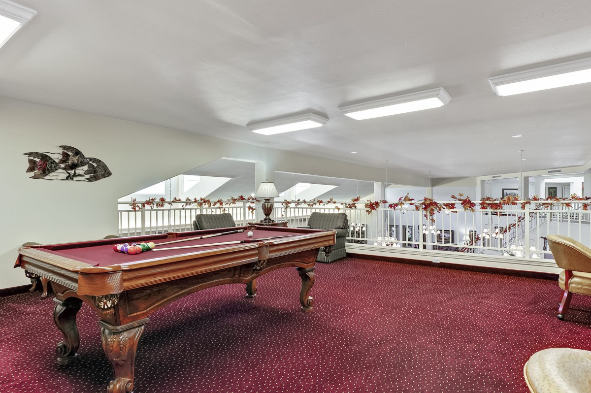 A spacious loft area with a billiards table and red carpet.