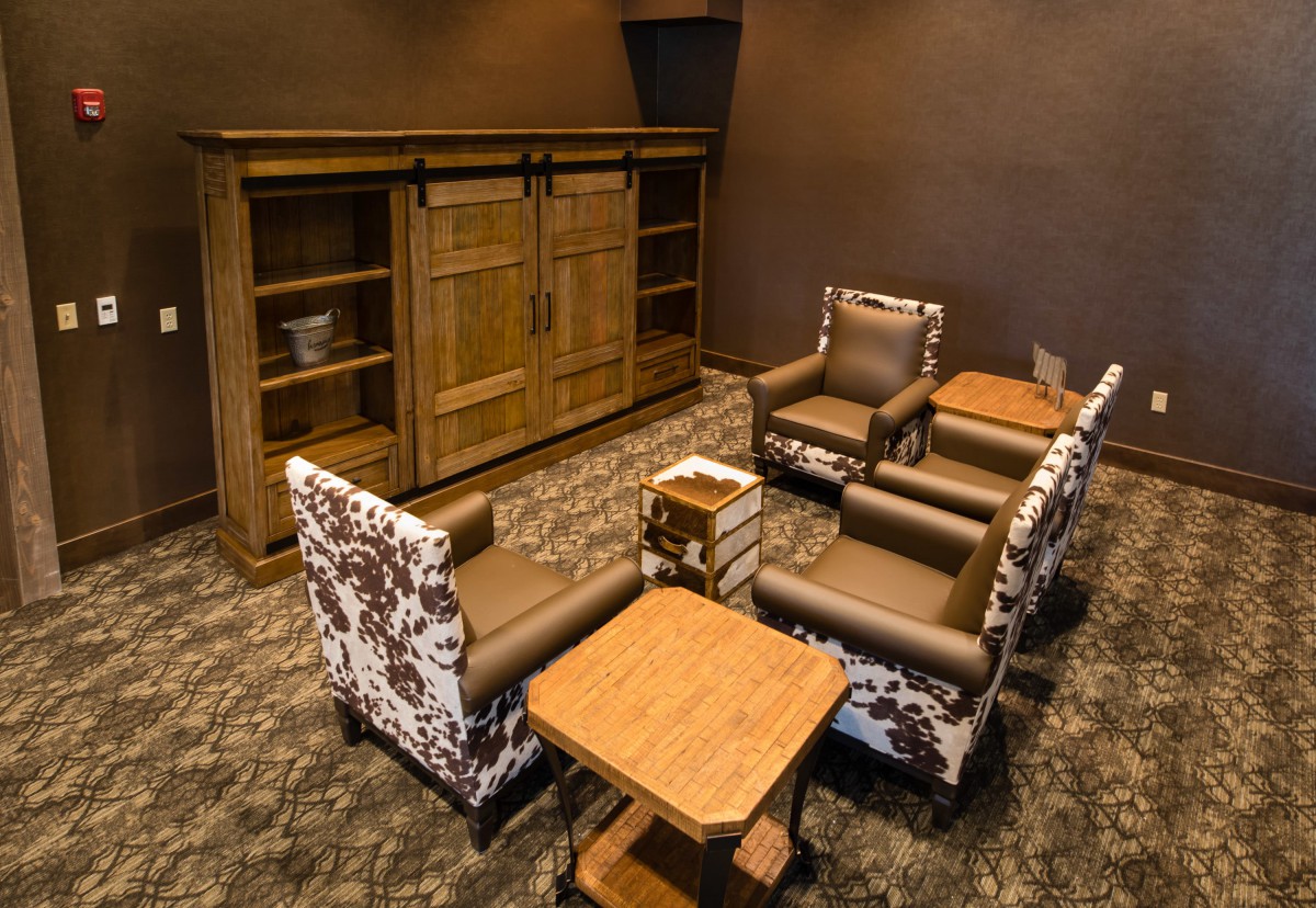 A cozy living room with armchairs, a wooden bookcase, and tables.