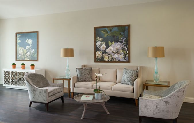 A cozy living room with a sofa, armchair, coffee table, and decorative artwork.