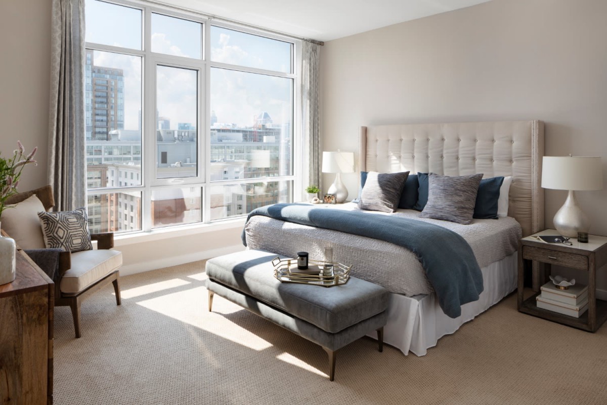 A modern and luxurious bedroom with large windows offering a stunning city view.