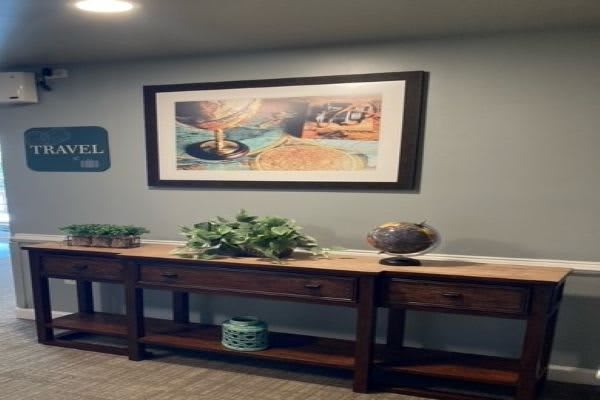A hallway with a painting above a wooden table, decorated with plants and a vase.