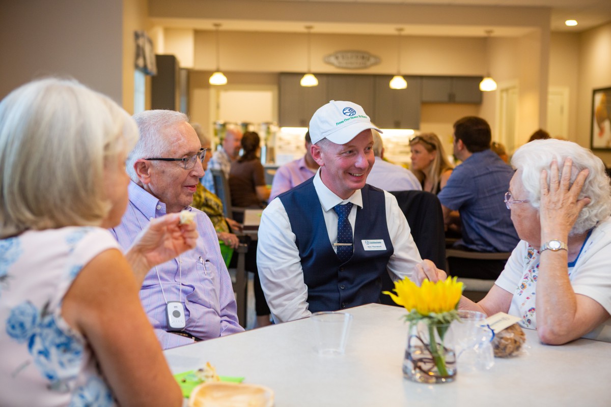 A group of people enjoying a conversation around a table in a well-lit dining area.