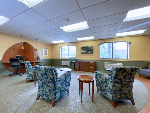 A cozy lounge area with comfortable seating, natural light filtering through the windows, and a welcoming atmosphere.