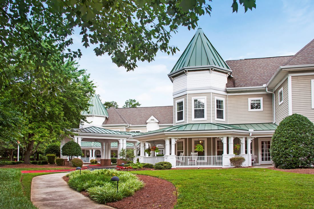 A charming, large house with a green roof and surrounding garden.