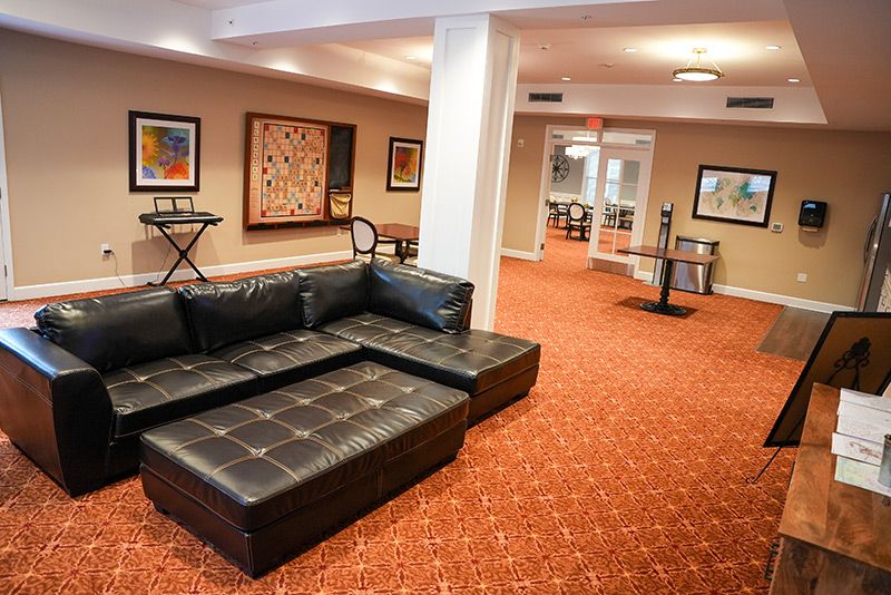A modern lounge area with a black leather sofa and colorful artwork on the walls.