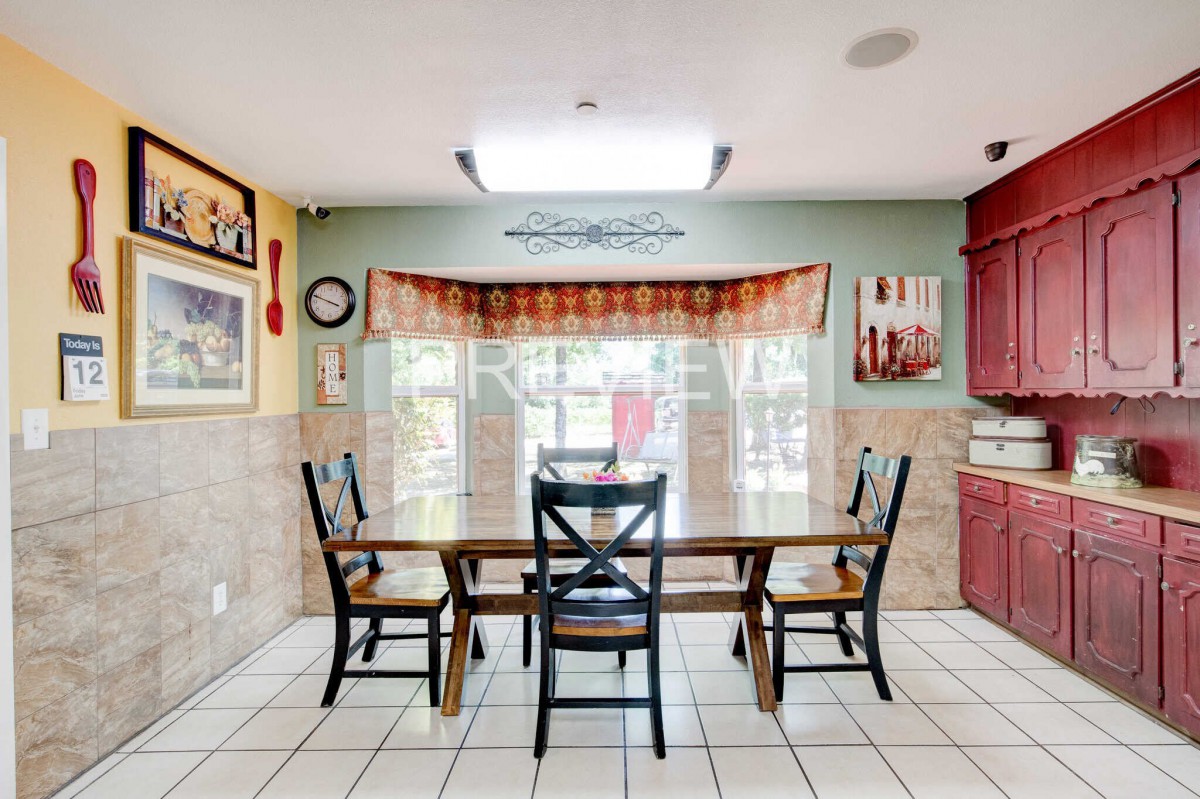 A cozy dining area with a wooden table and chairs, brightened by natural light from a large window with patterned curtains.