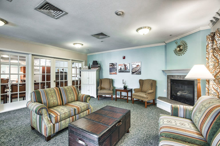 A cozy living room with comfortable seating, a fireplace, and decorative art on the walls.