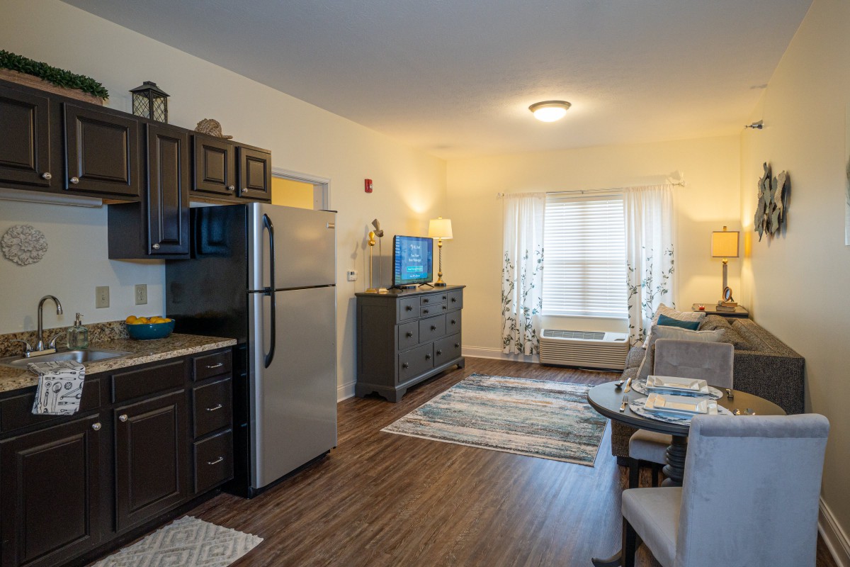 A cozy apartment interior featuring a living room and kitchen area with modern furnishings and hardwood floors.