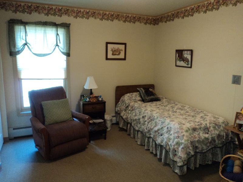 A cozy bedroom featuring a single bed and an armchair by the window