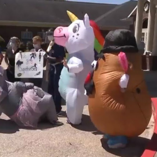 Participants in creative inflatable costumes, including a unicorn and a potato, engage with the crowd at an outdoor event.