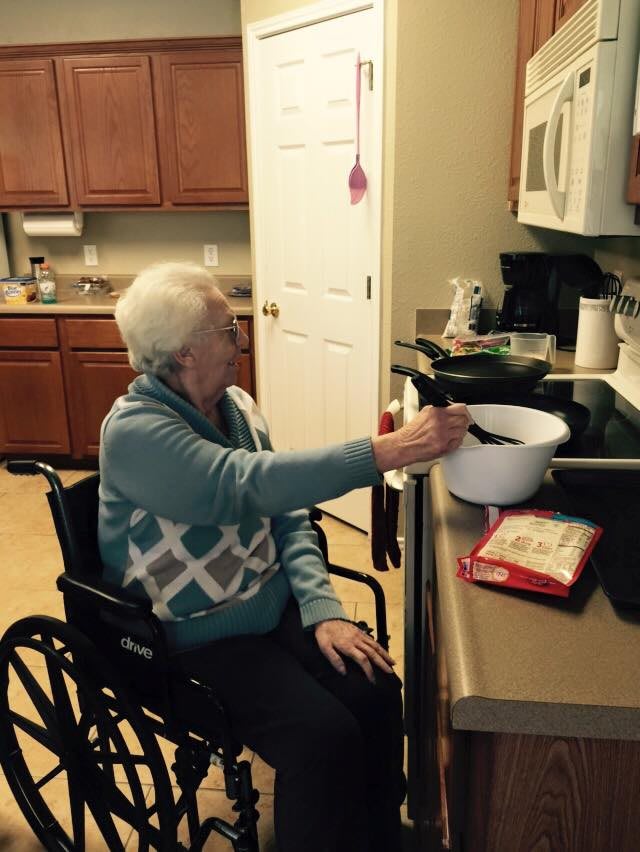 An elderly person in a wheelchair cooking in the kitchen, emphasizing accessibility and independence.