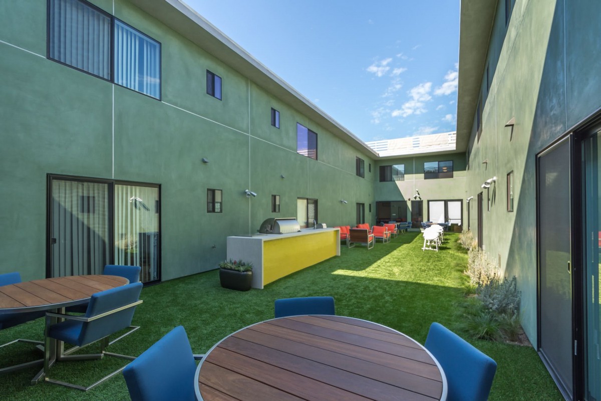 A modern courtyard with patio furniture between two residential buildings.
