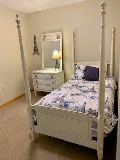 A cozy bedroom with a four-poster bed and matching dresser.