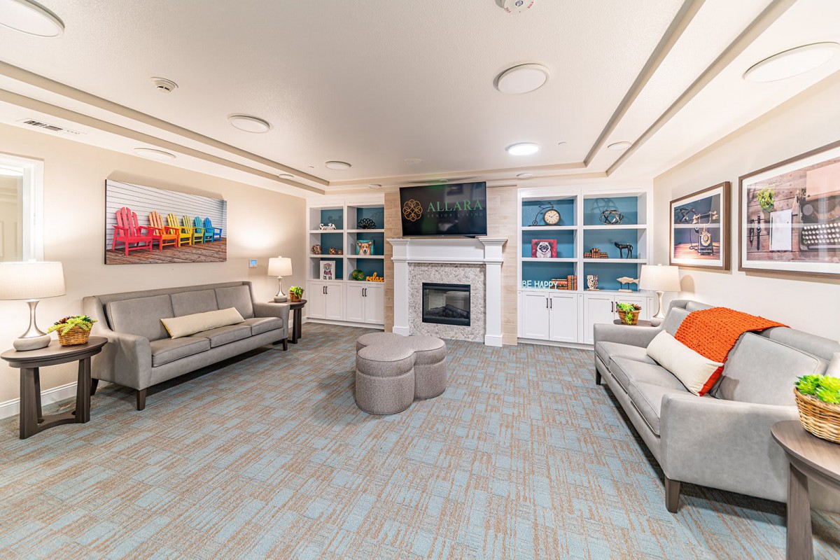 A modern living room with gray sofas, a central fireplace, and built-in bookshelves.